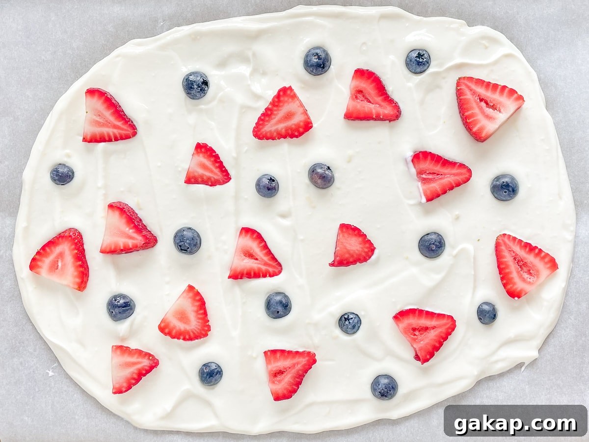 Yogurt spread on a pan and topped with blueberries and strawberries