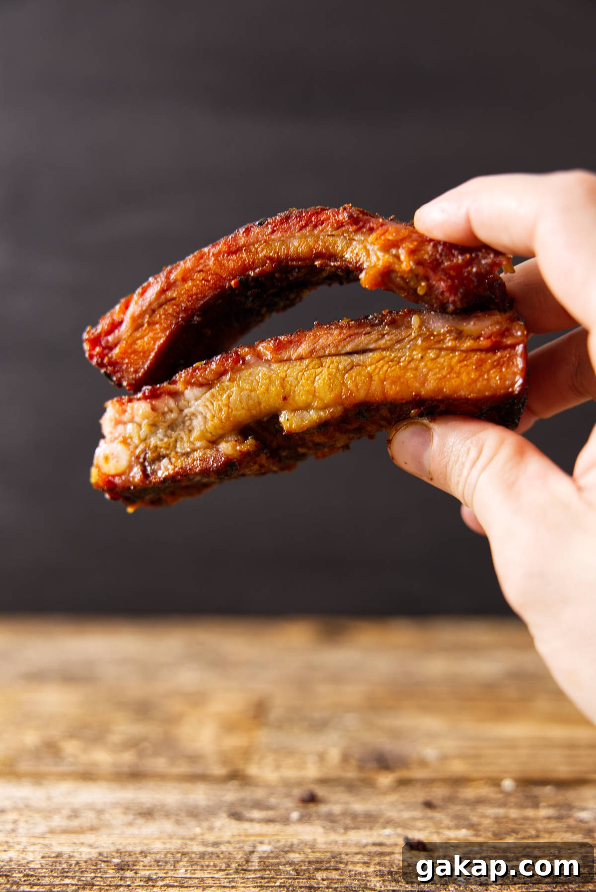 Baby Back Ribs vs St. Louis Ribs: Key Differences and Cooking Tips 3 Hand holding cooked pork loin back ribs vs spare ribs.