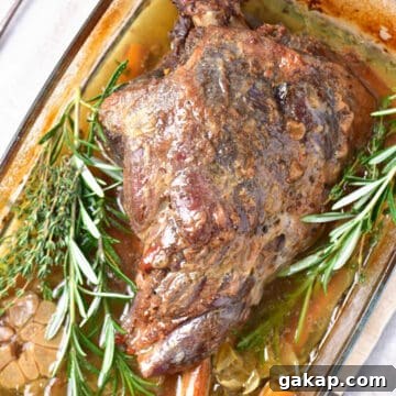 Perfect Slow-Roasted Leg of Lamb Recipe for Tender Meat 12 Whole slow roasted leg of lamb with fresh herbs on a glass dish.