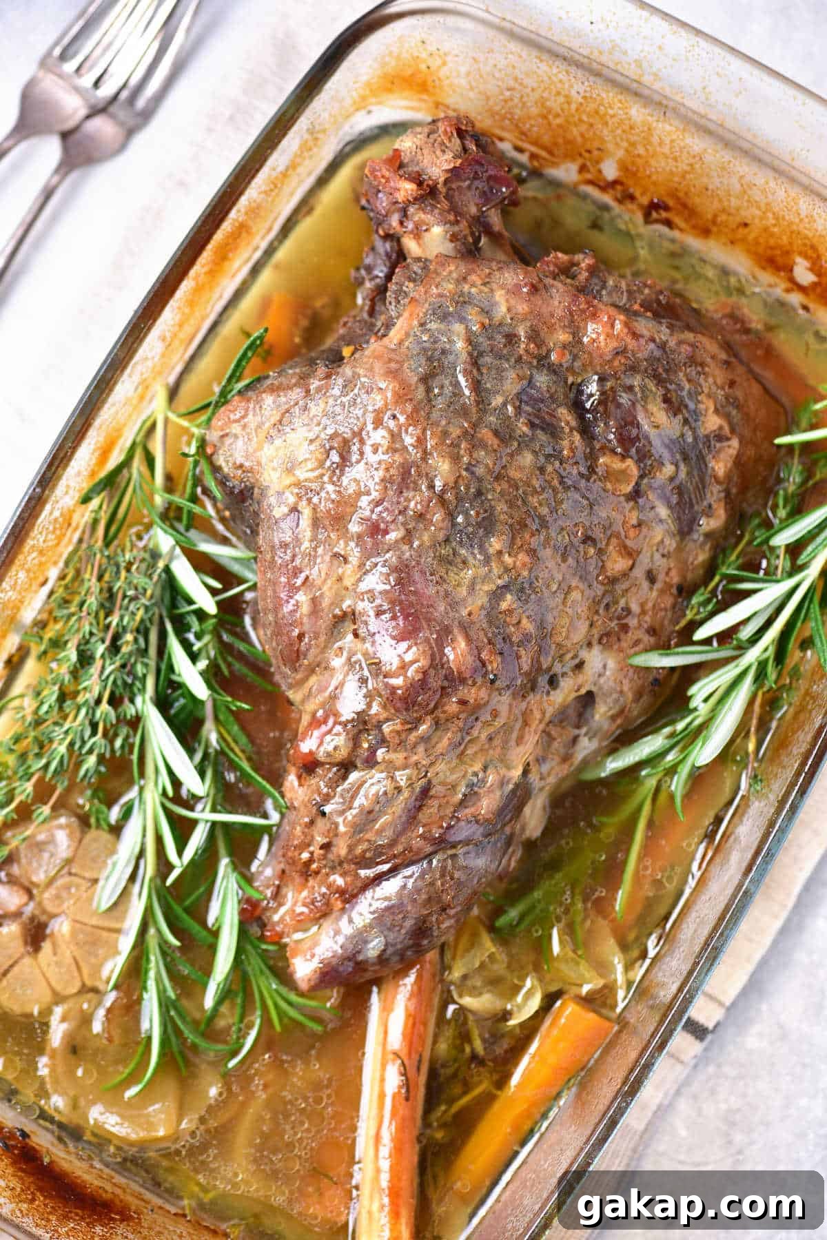 Perfect Slow-Roasted Leg of Lamb Recipe for Tender Meat 3 Fresh herbs around a juicy roasted leg of lamb in a glass dish.