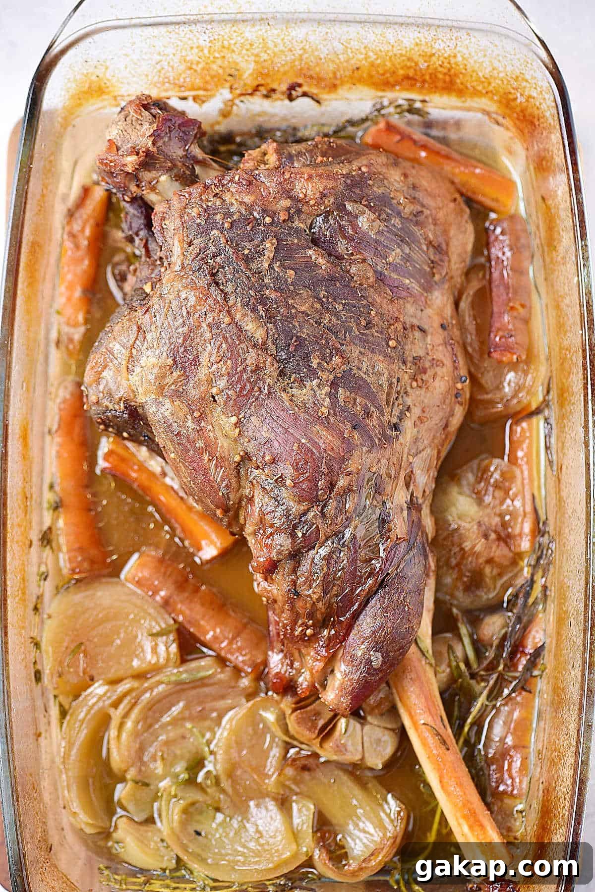 Perfect Slow-Roasted Leg of Lamb Recipe for Tender Meat 6 Oven roasted leg of lamb with carrots and onions in a glass dish.