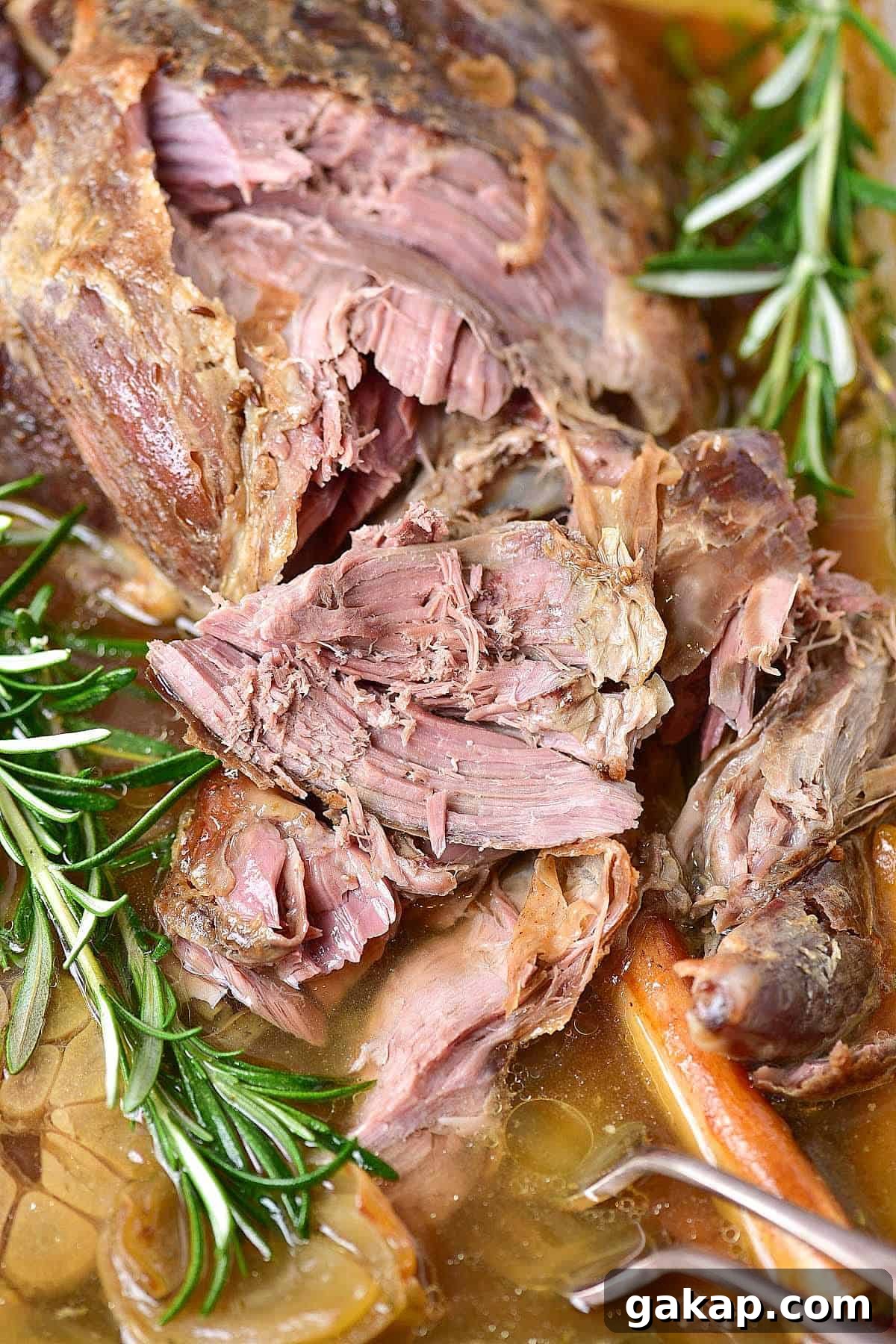 Perfect Slow-Roasted Leg of Lamb Recipe for Tender Meat 7 Pulled apart lamb meat with fresh rosemary. Close up image.