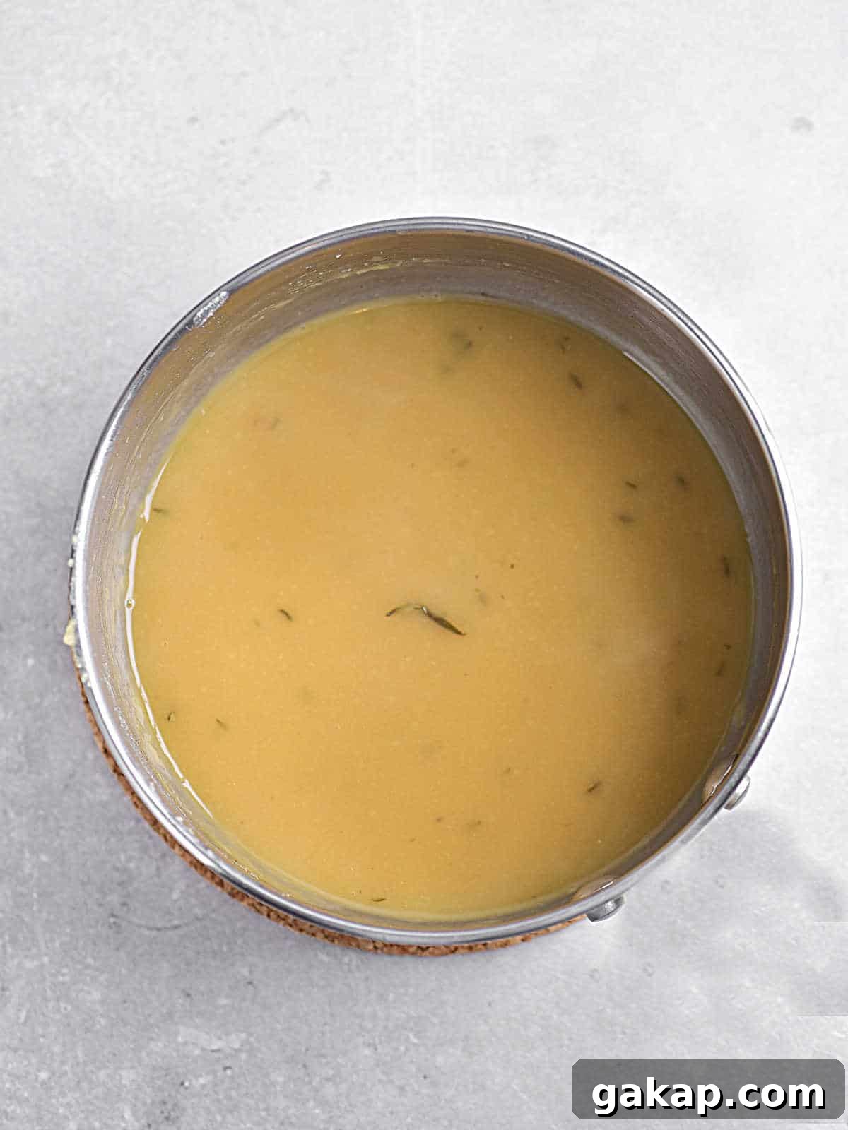 Perfect Slow-Roasted Leg of Lamb Recipe for Tender Meat 9 Metal pan with lamb gravy on a light grey surface.