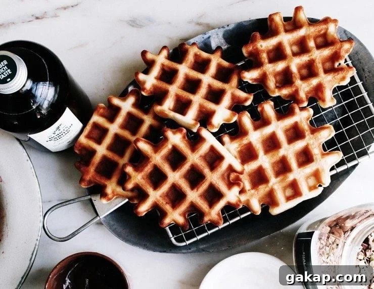 Homemade Belgian waffles on a platter with maple syrup on the side.