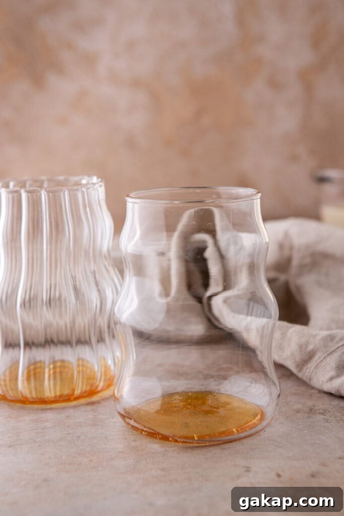 Honey Oatmilk Latte Recipe: Hot & Iced Starbucks-Style Guide 4 Clear glass with honey at the bottom, the first step in making a honey oat milk latte.