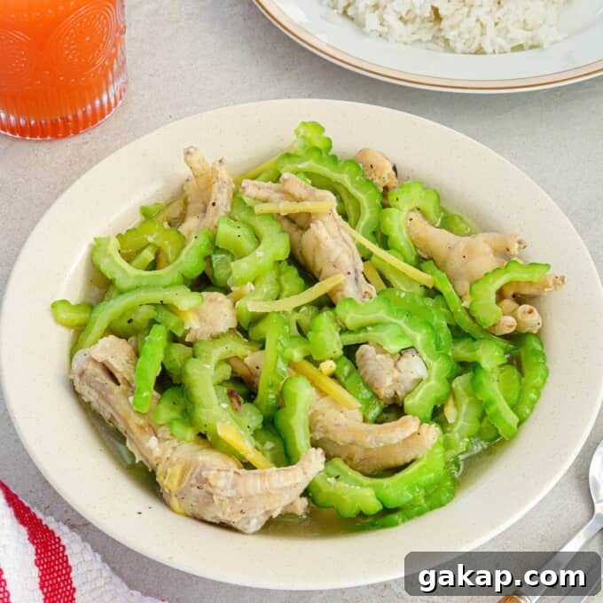 Bitter Melon with Chicken Feet Recipe: Filipino Style Stew 7 Ampalaya with Chicken Feet in a white bowl with a plate of steamed rice in the background.