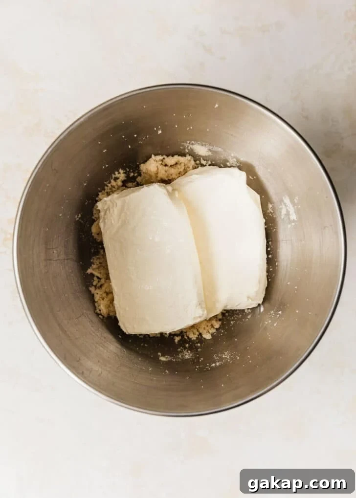 A silver bowl of cream cheese, butter, and sugar on a tan counter.