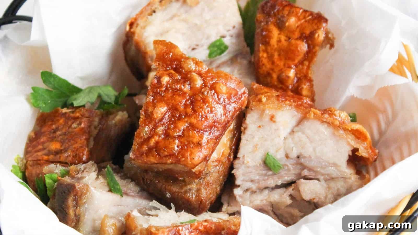 A basket of crispy roasted pork belly chunks garnished with parsley, served in a white paper-lined wicker basket.