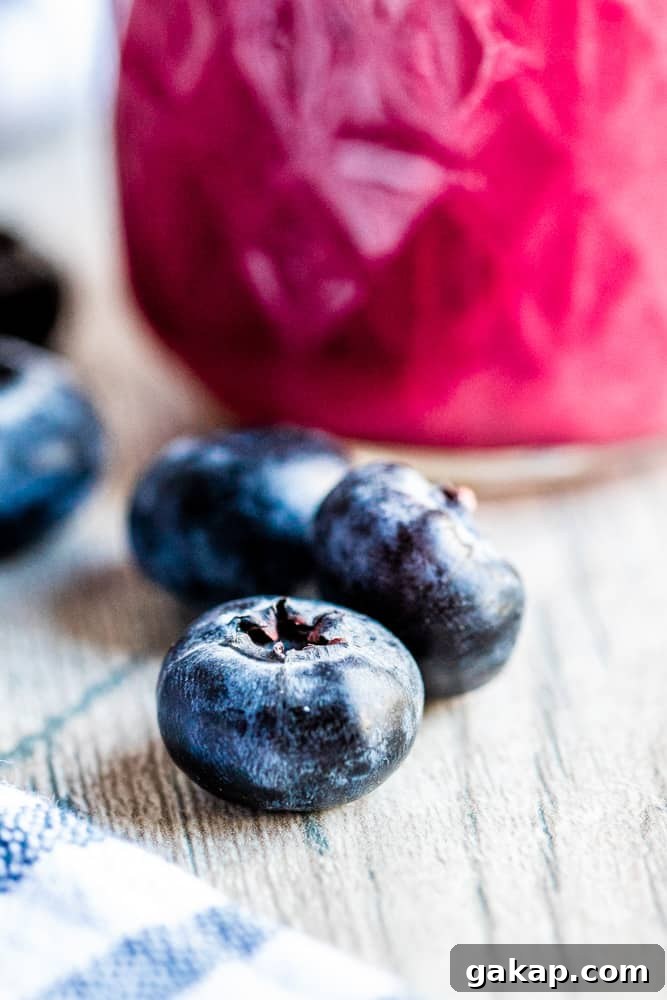 Close up shot of a blueberry with dressing in the background.