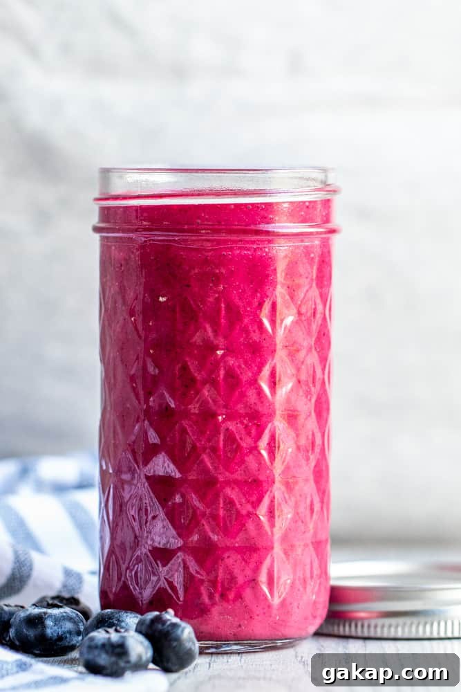 Straight on shot of blueberry vinaigrette in a mason jar on a white counter.