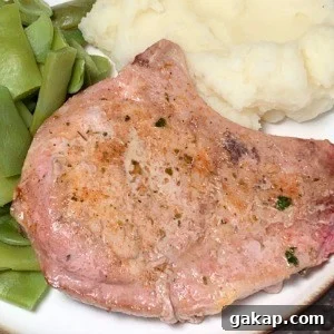 Close up baked pork chop with a curved rib bone on a dinner plate with