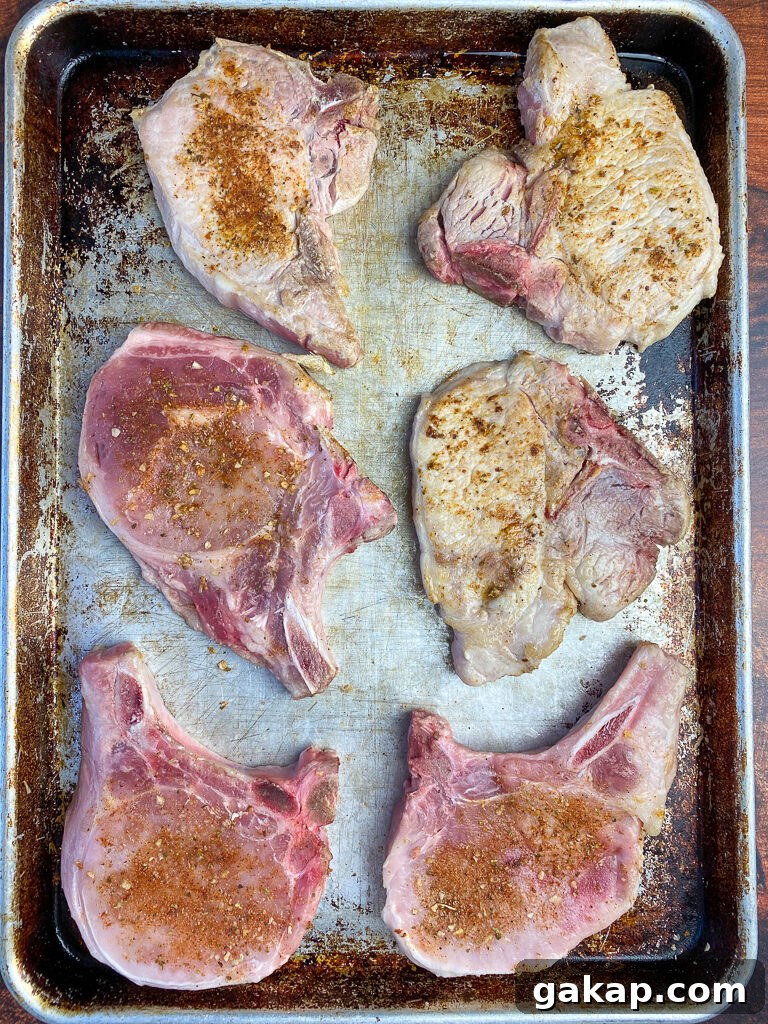 Sheet pan of oven baked pork chops with half raw and half that have been seared