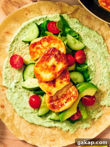 Seared halloumi, creamy cilantro sauce, and fresh veggies on a wrap.
