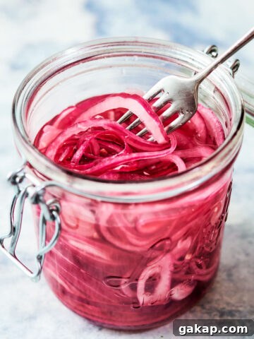 Quick pickled onions in a glass jar with a fork.