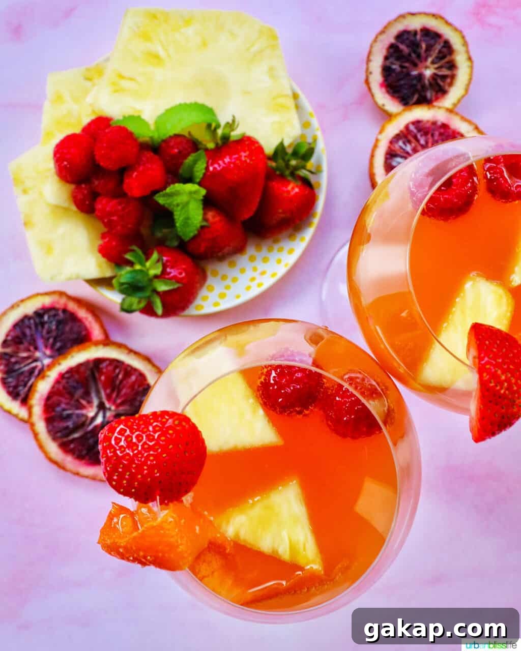 sliced fruit with two glasses of tropical sangria shot from above