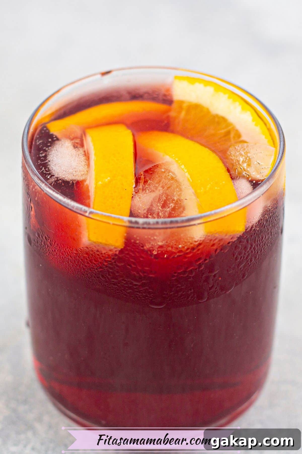 Sparkling Kombucha Mocktail Recipe for Refreshing Summer Sips 6 Red kombucha mocktail in a glass garnished with orange slices.