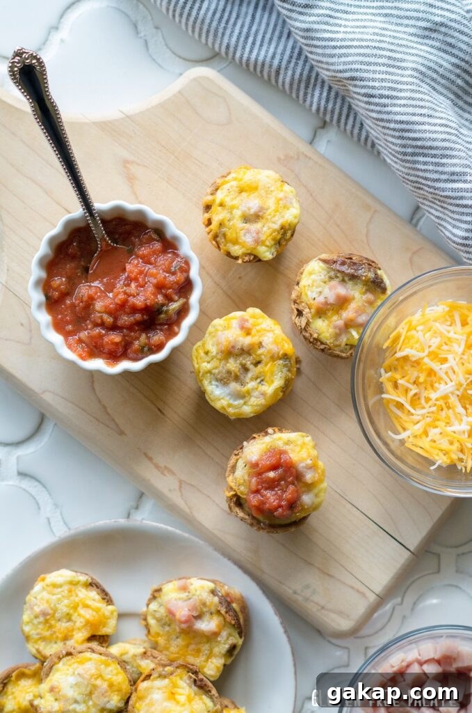 Mini Quiches on a cutting board next to a bowl of cheese and a bowl of salsa with a spoon