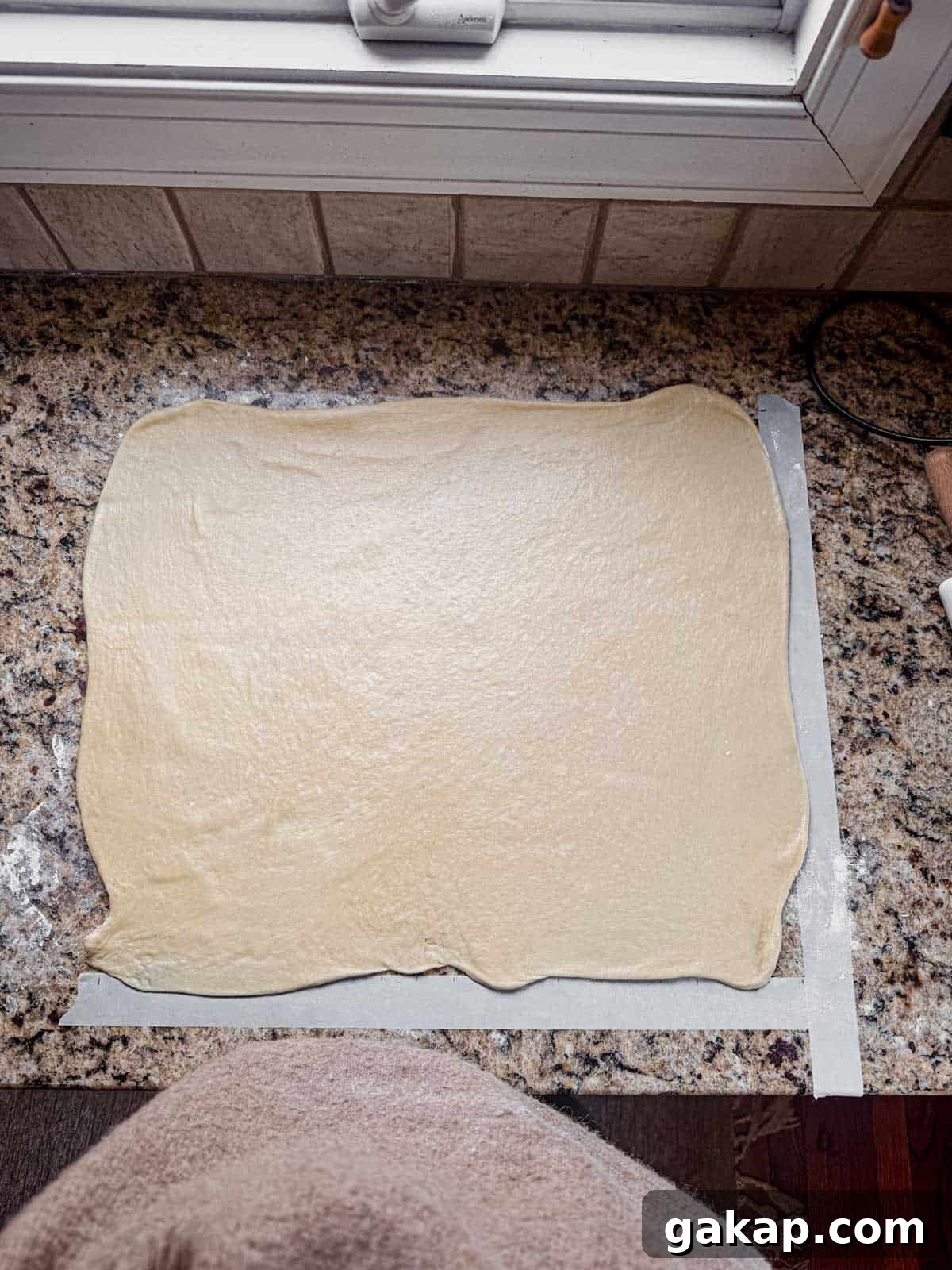 cinnamon roll dough rolled out into a rectangle on a counter.