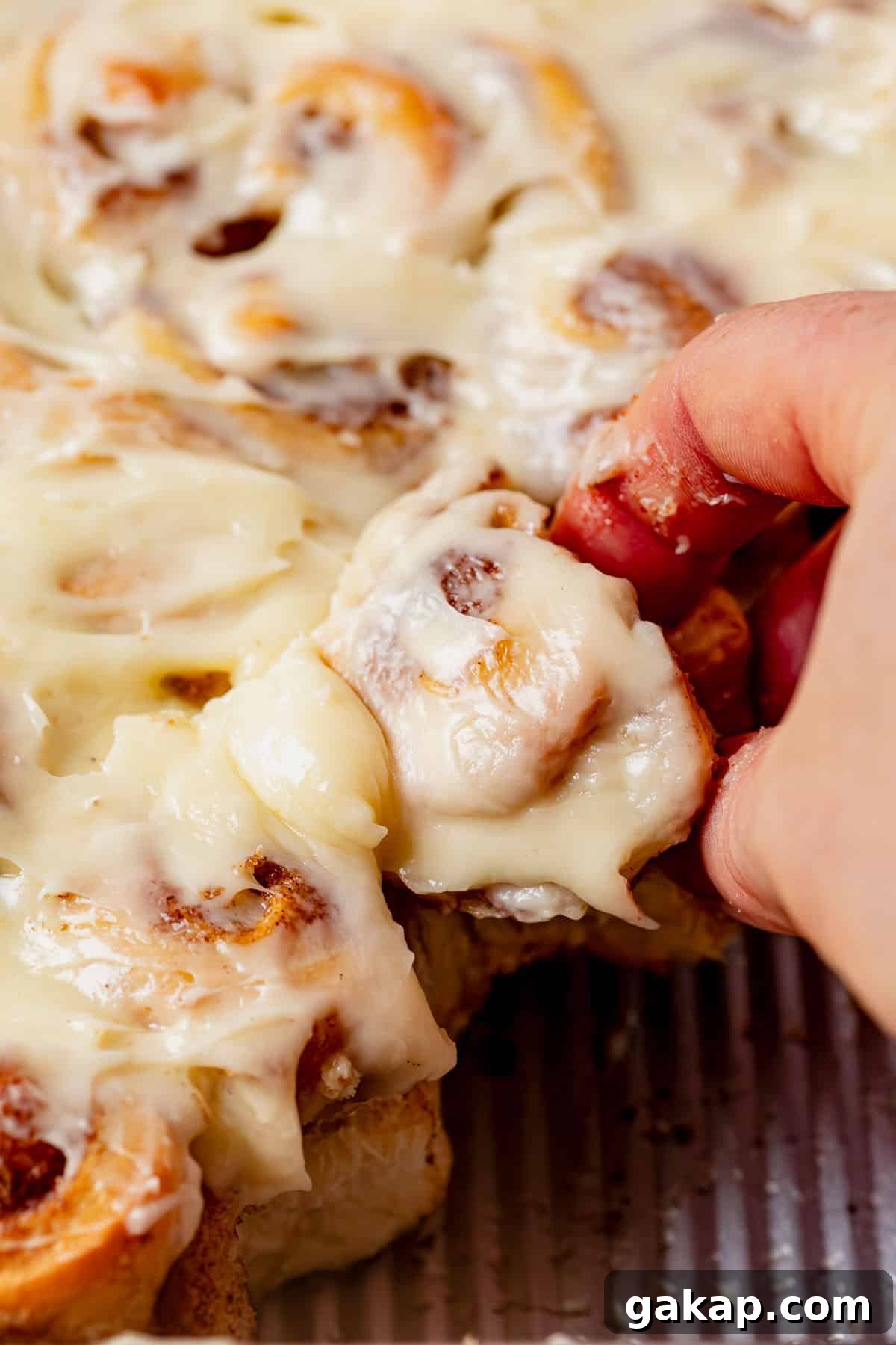 pulling a mini cinnamon roll apart from the other rolls.