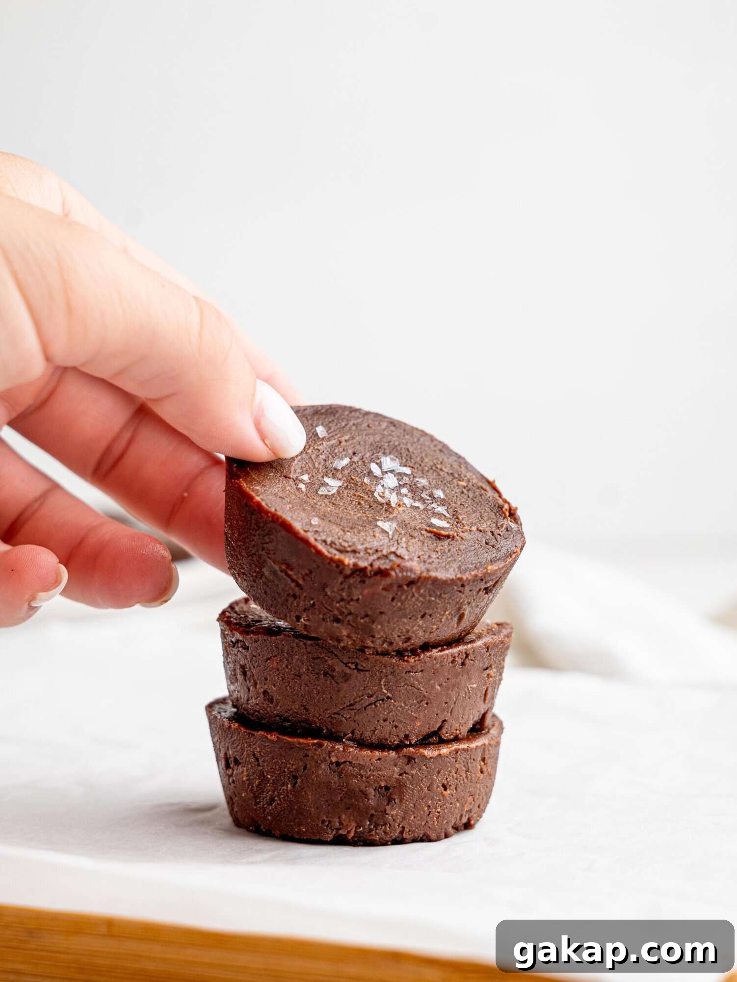 Three chocolate fudge cups stacked on top of each other, a hand is lifting the top one.