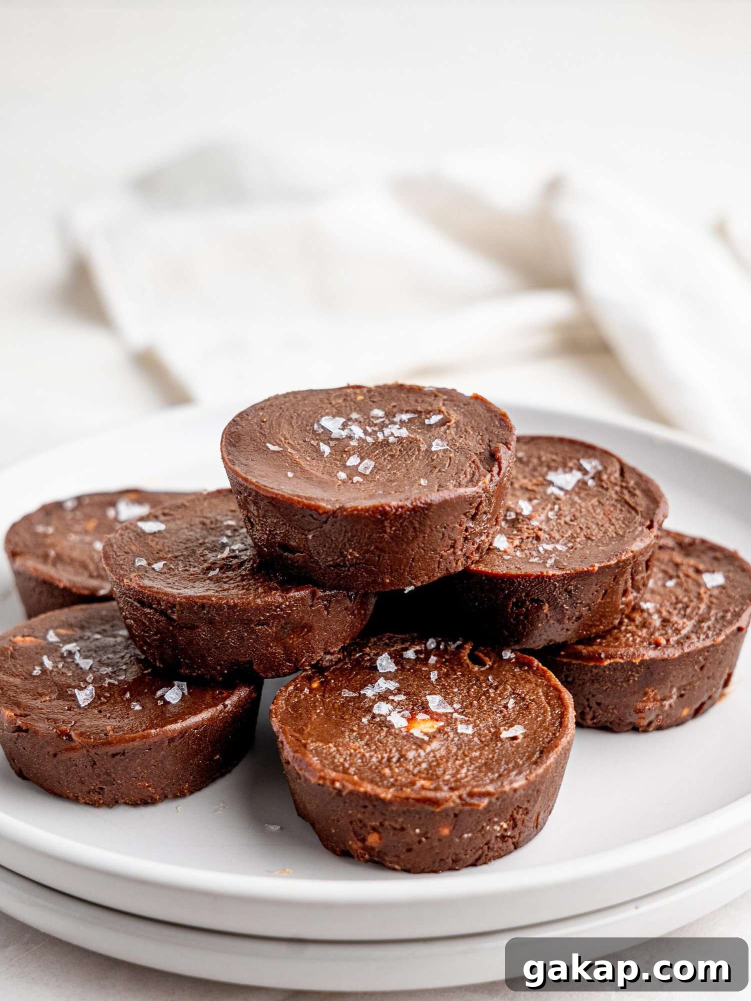 Healthy chocolate fudge cups stacked on a white plate.