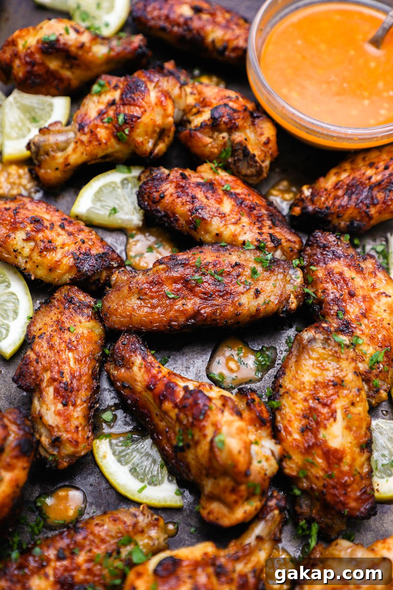 Crispy Lemon Garlic Chicken Wings Recipe 7 A large baking tray filled with lemon garlic chicken wings sitting next to a bowl of lemon garlic marinade