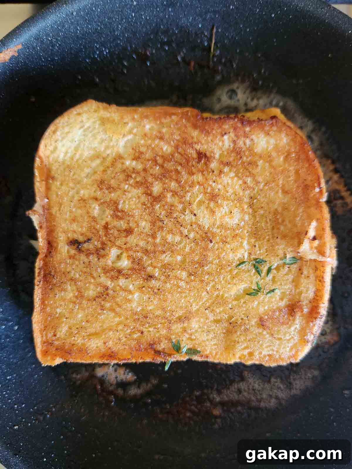 Grilled cheese cooking in a black skillet.