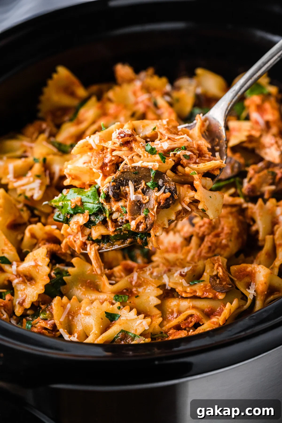 Creamy Slow Cooker Chicken and Bacon Pasta Recipe 2 scooping chicken bacon pasta out of a crockpot.