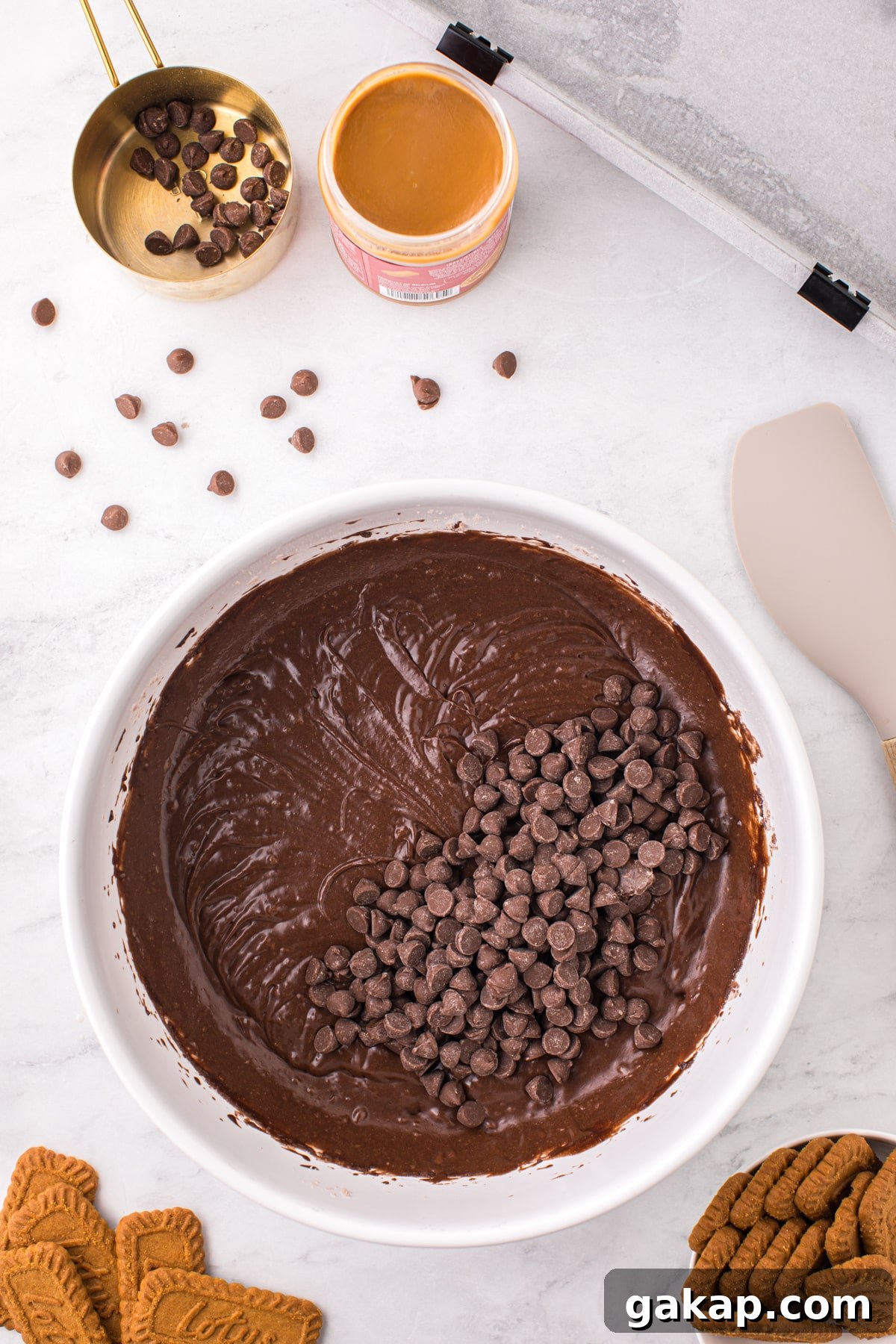 A bowl of brownie batter with chocolate chips added into the batter.