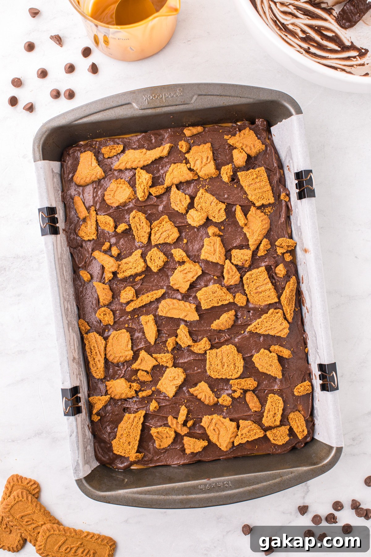 A baking pan filled with brownie batter and topped with cookie pieces.
