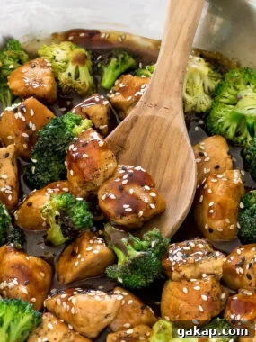 honey garlic chicken in a large skillet with a wooden spoon