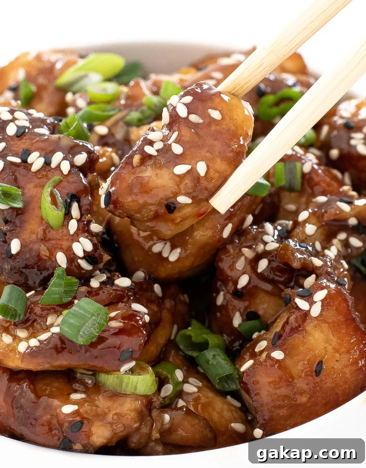 author picking up asian chicken bite with wooden chopsticks