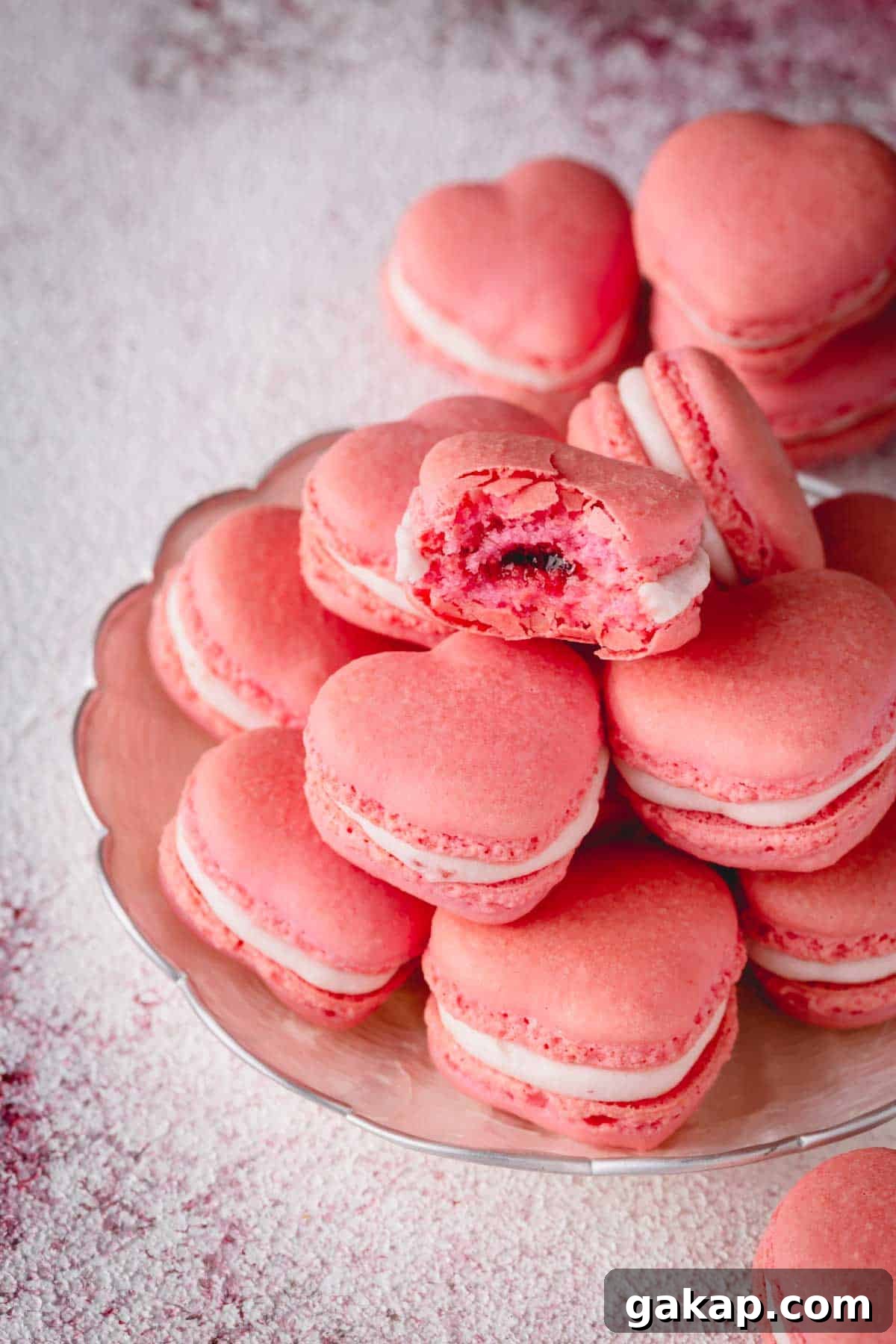 Stack of pink heart macarons with one macaron is bitten.