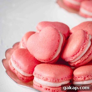 Pink heart-shaped macarons stacked on a plate.