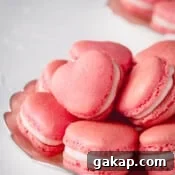 Pink heart-shaped macarons stacked on a plate.