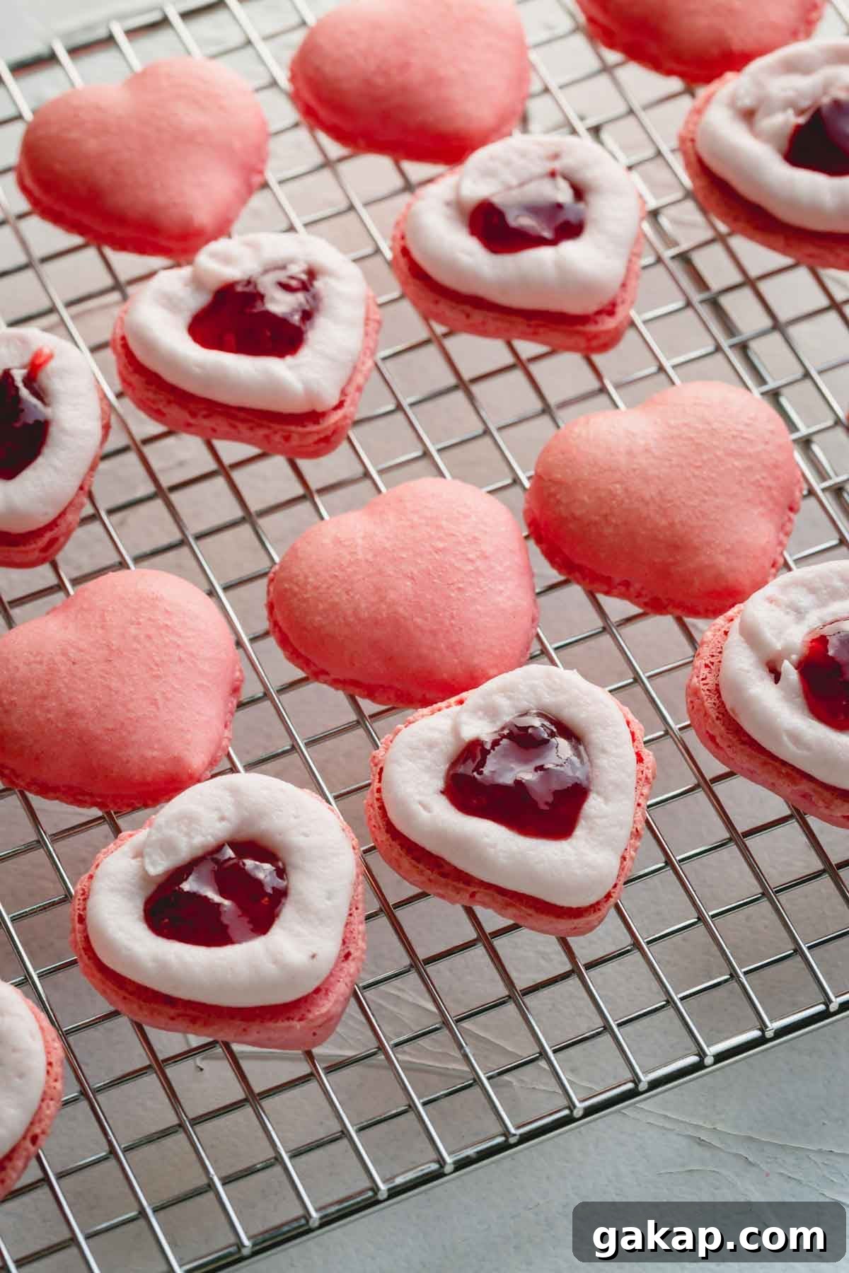 Pink macaron shells with piped buttercream border and jam in the center.