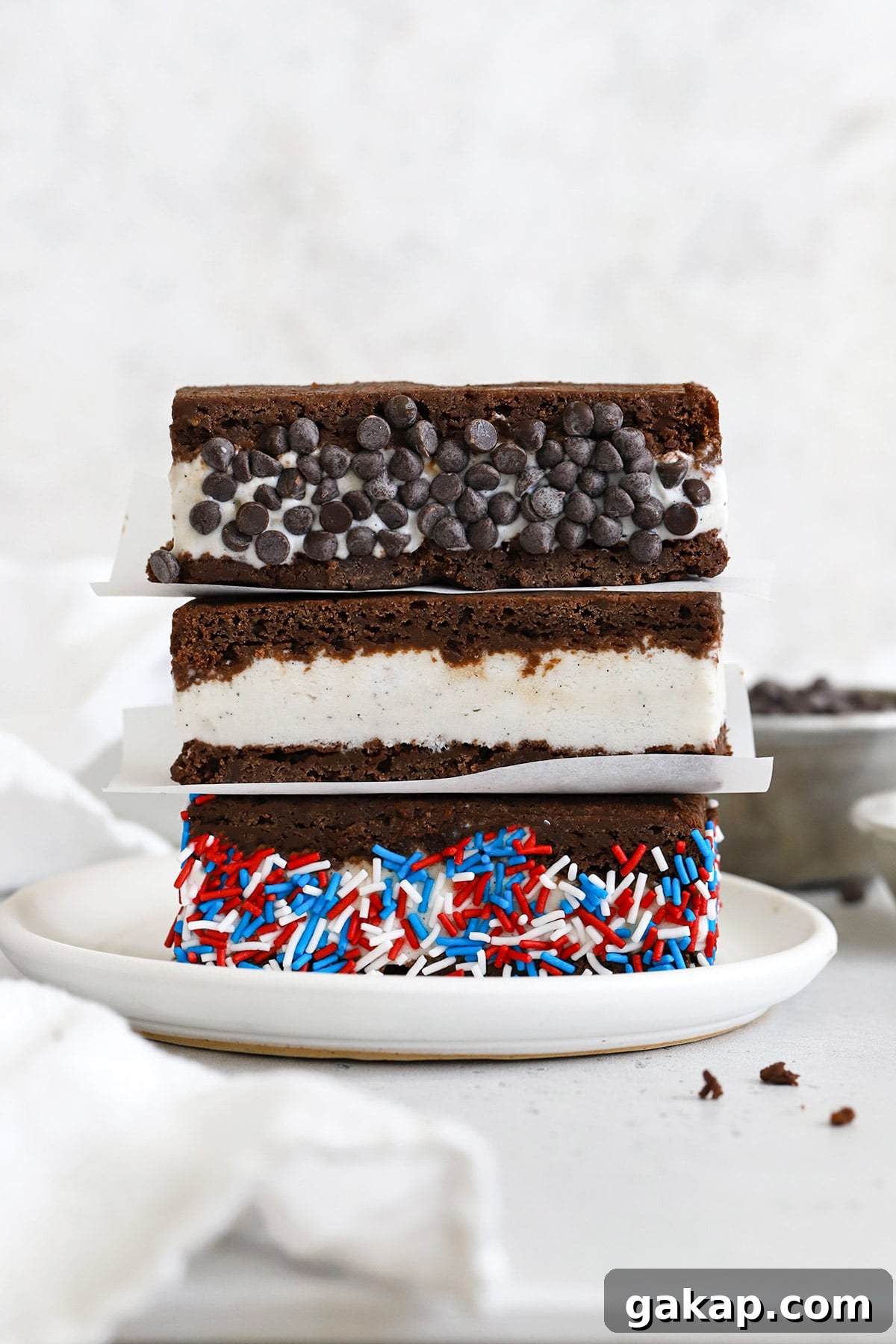 Gluten-Free Brownie Ice Cream Sandwich Recipe 10 Three gluten-free brownie ice cream sandwiches on a plate. One is rolled in chocolate chip and one is rolled in red, white, and blue sprinkles