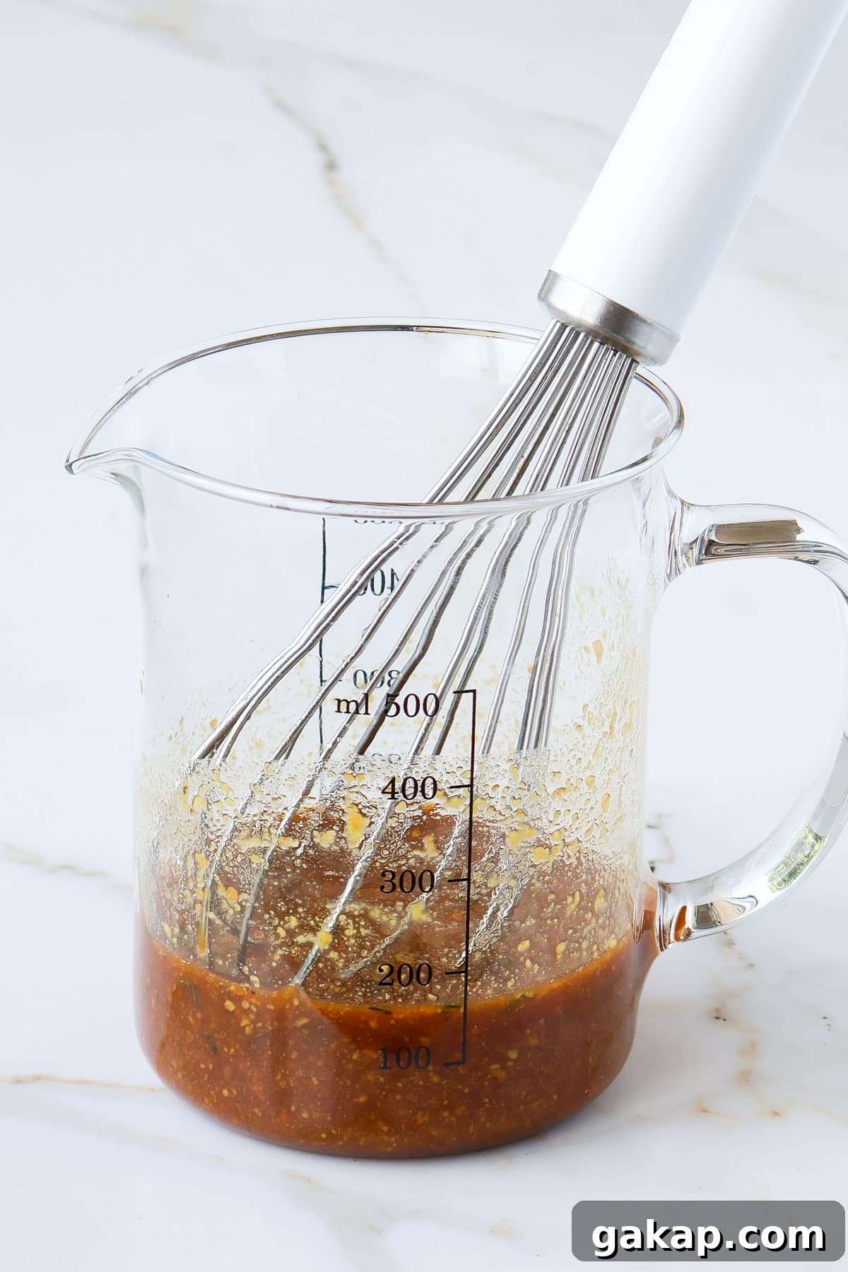 Maple sauce in a jug with a whisk.