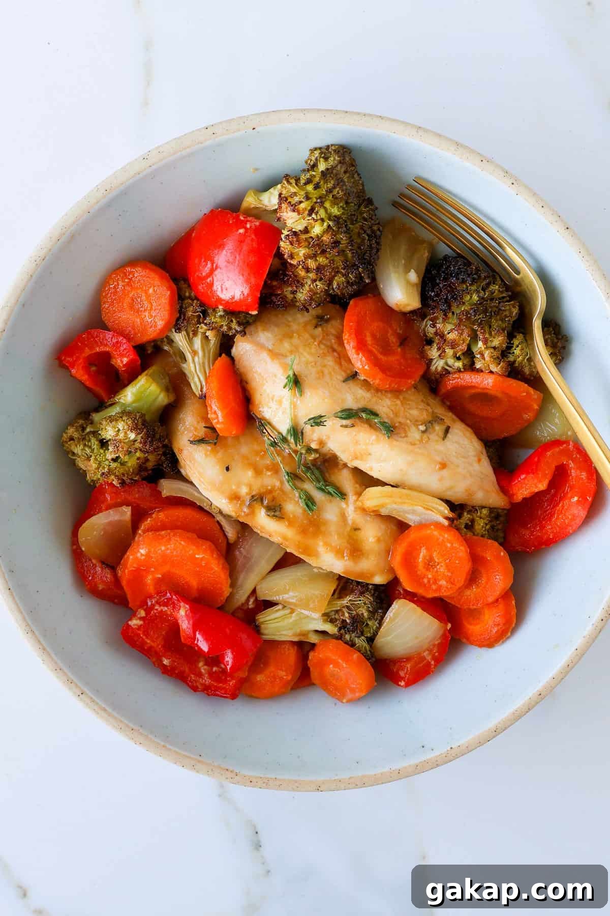 Baked maple chicken and vegges in a bowl with a fork.