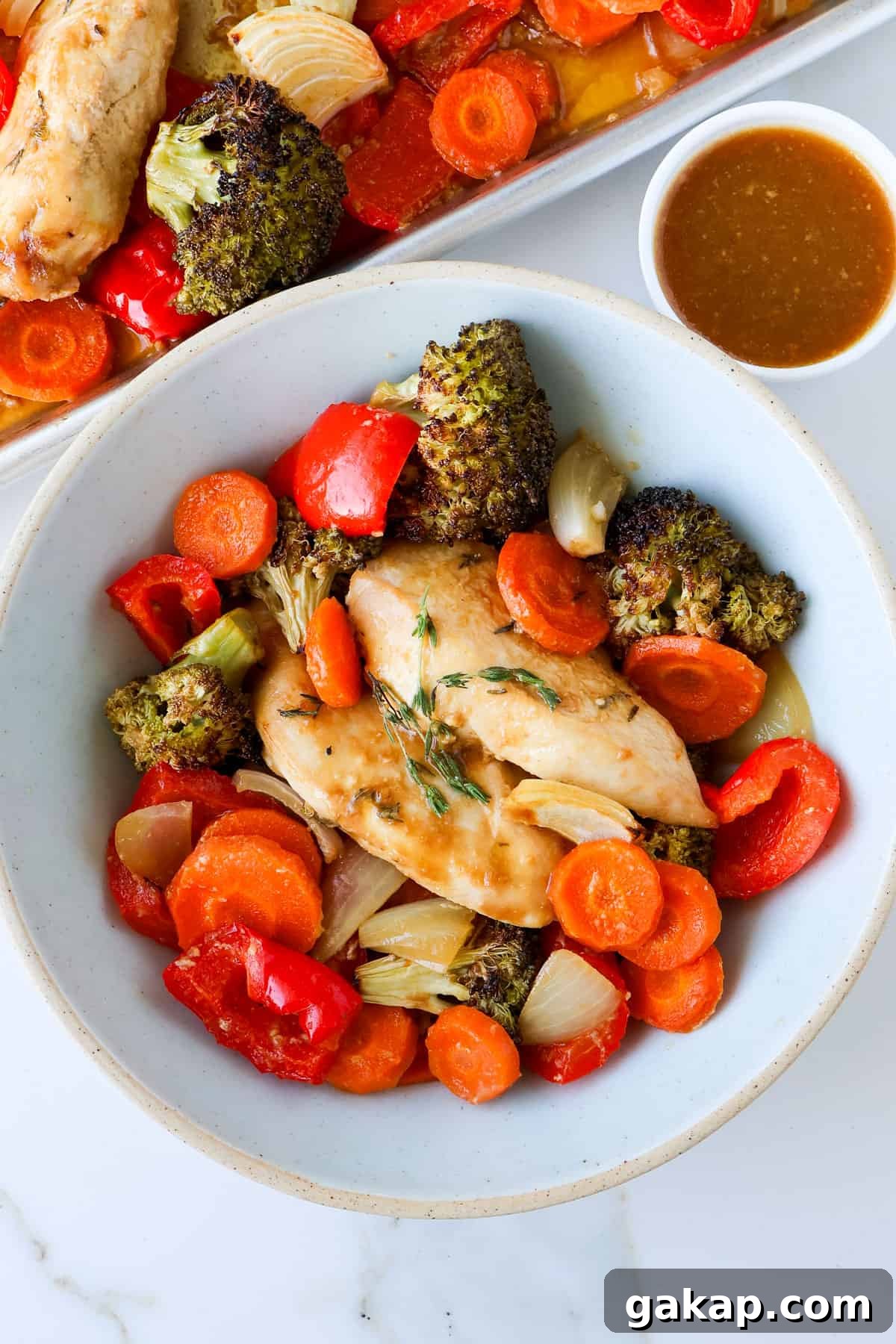 Chicken and vegges in a bowl with sauce on the side.