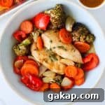 Baked maple chicken and vegges in a bowl with sauce on the side.