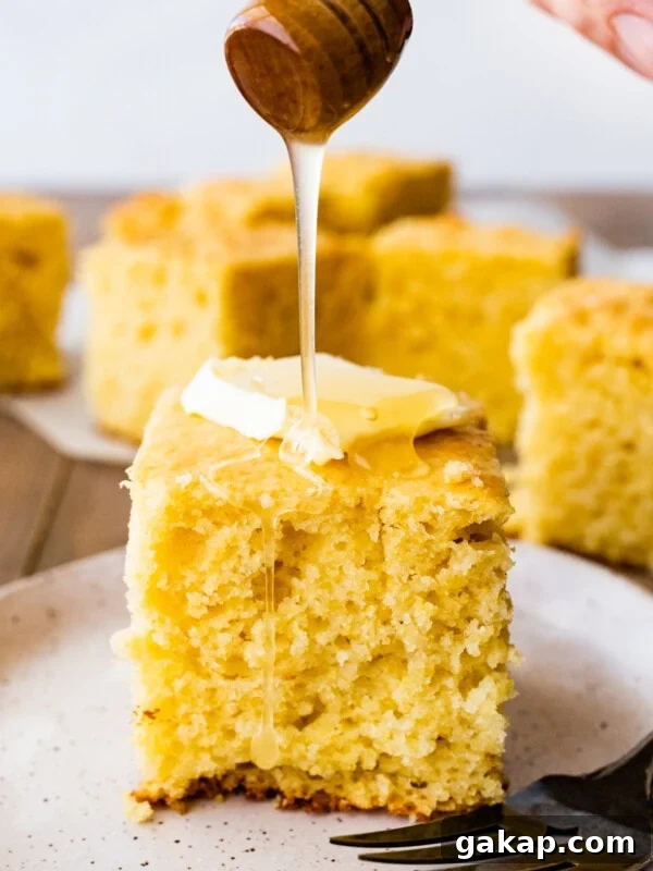 Honey pouring onto a slice of sweet cornbread with butter.