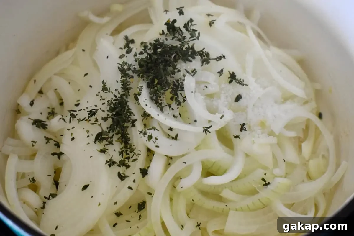 Sliced onions in a dutch oven with thyme and kosher salt. 