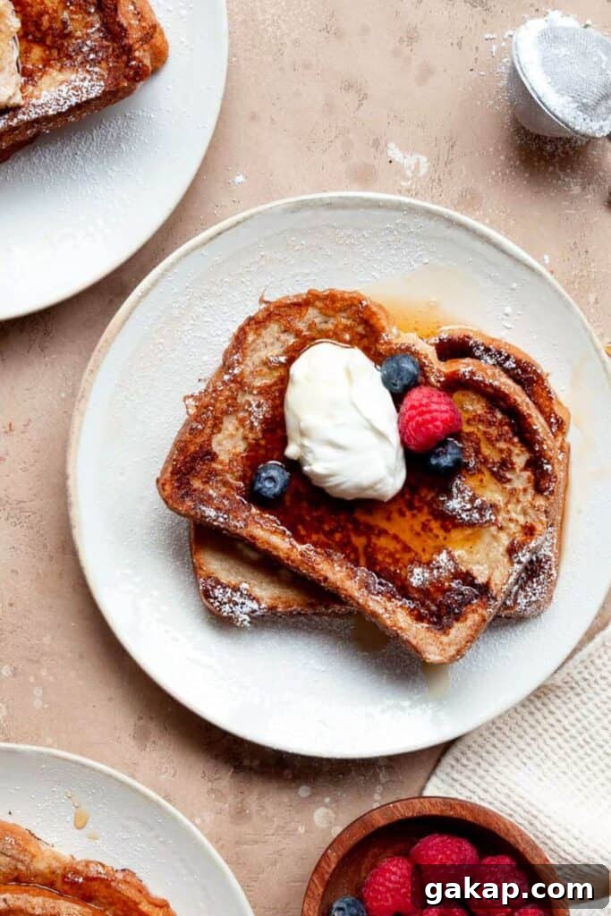 high-protein french toast on a plate topped with Greek yogurt, berries, and syrup