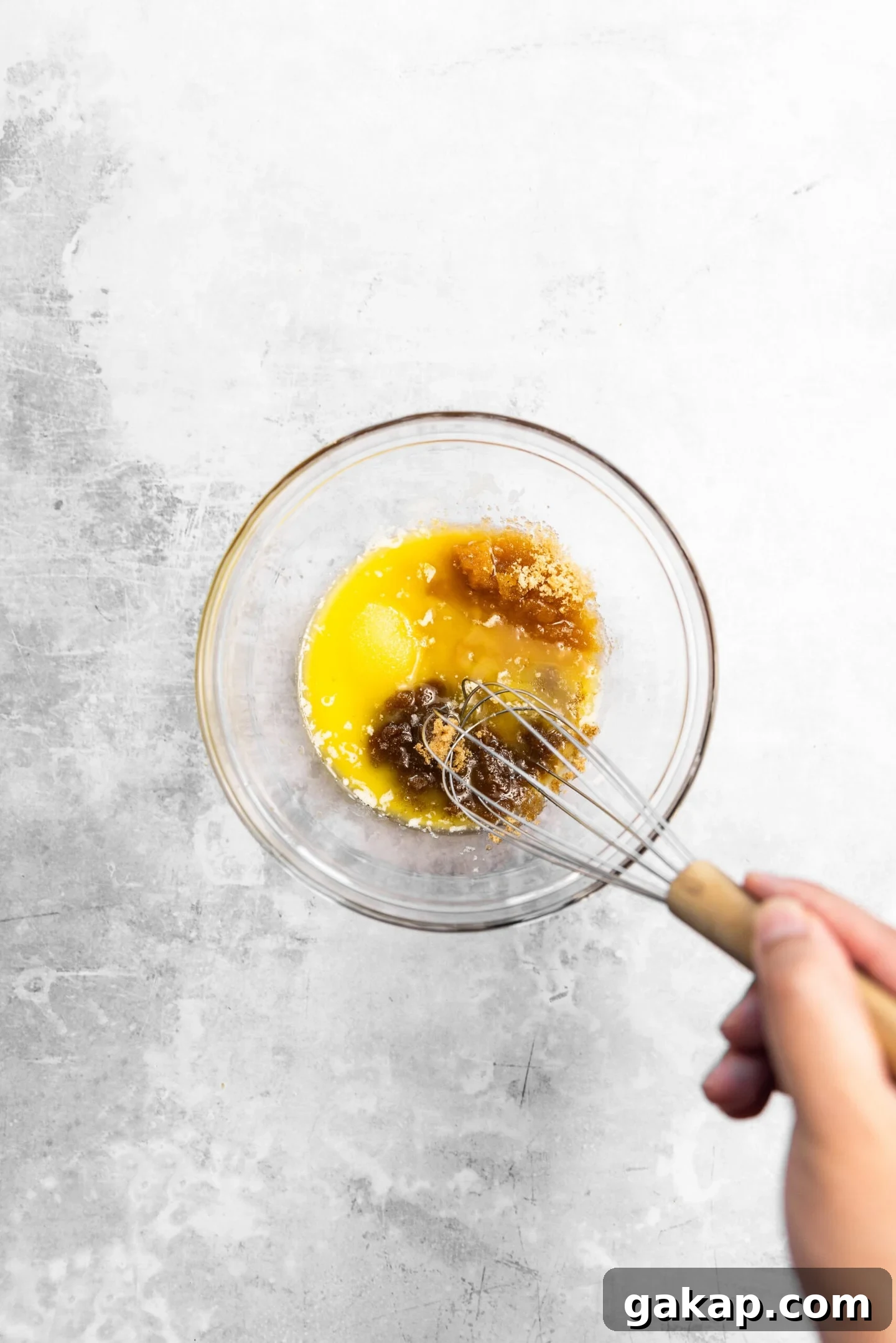 Melted butter and sugars being whisked together.