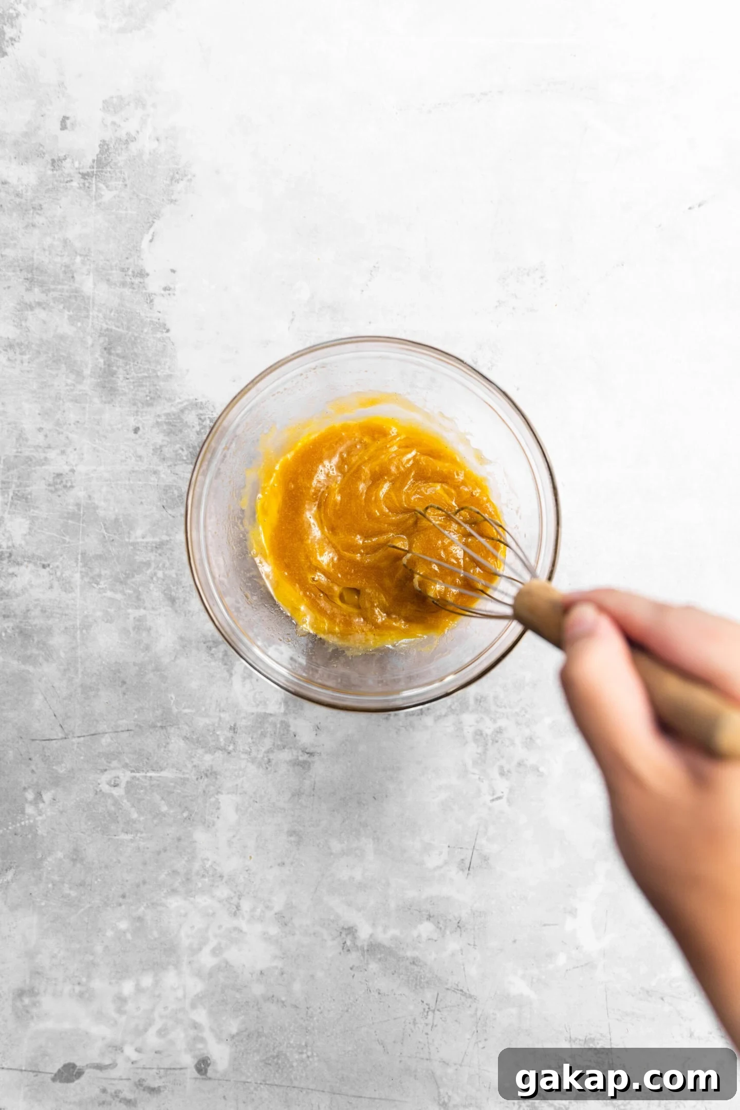 Egg being whisked into sugar mixture.