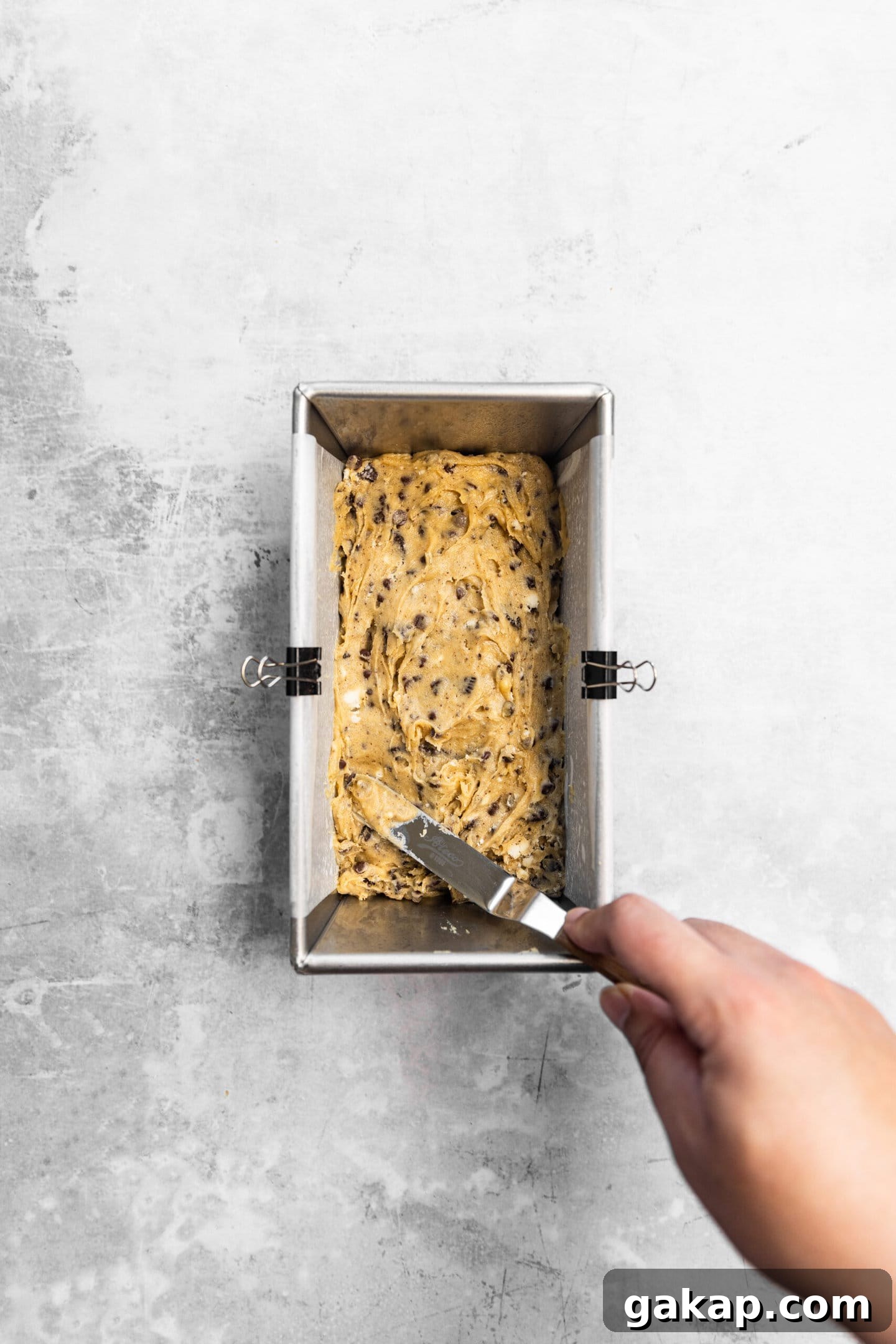 Oreo blondie batter being spread into prepared baking pan.