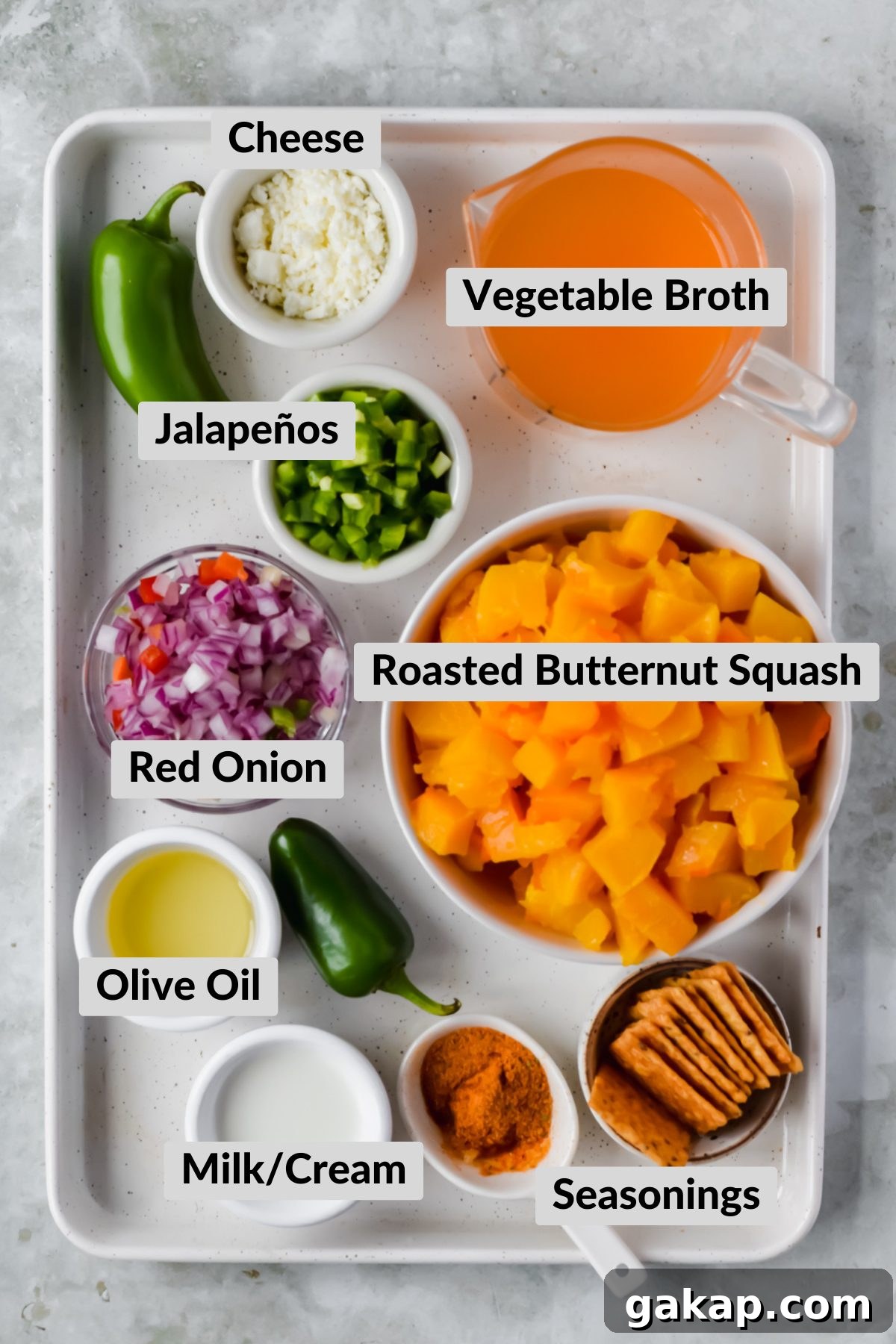 ingredients for spicy butternut squash soup in individual bowls on white sheet pan.
