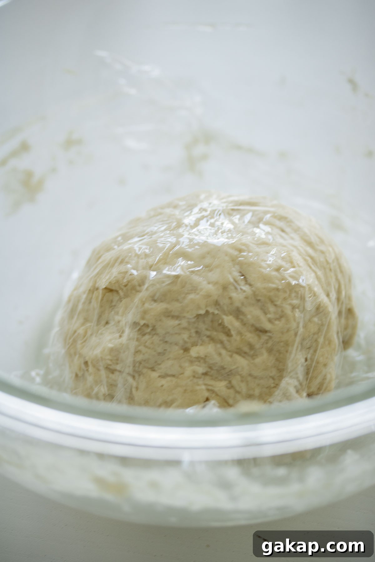 Dough covered, resting inside a glass bowl.