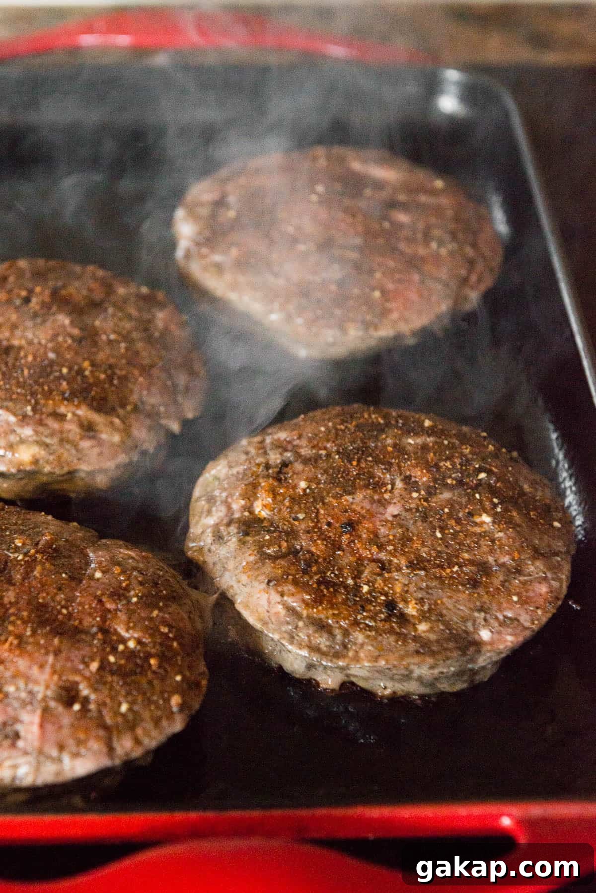 seasoned hamburger patties cooking on griddle